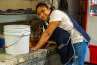 A cheerful woman cleaning in an industrial kitchen in Ciudad de México, showcasing hard work and dedication.